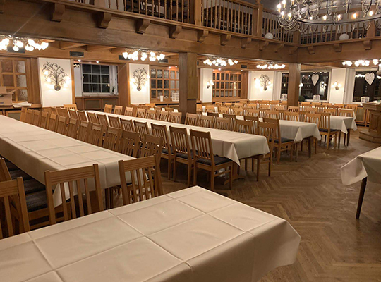 Durch Kronleuchter hell beleuchteter riesiger Speisesaal mit Holzeinrichtung