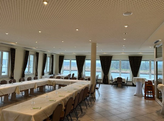 Großer Speisesaal mit langen Tischtafeln in U-Form inklusive wundervollem Blick auf den schönen Elbsee