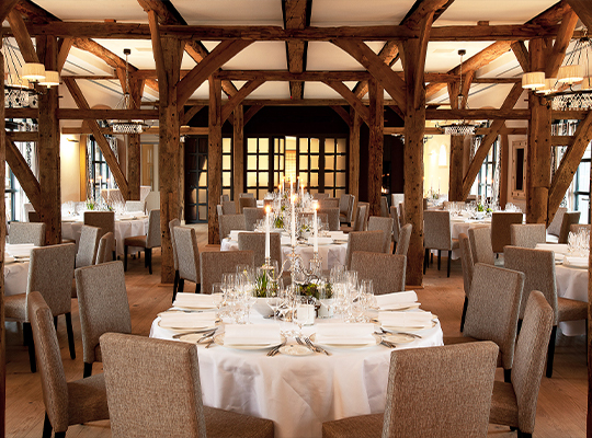 Eindrucksvoller Saal mit rustikalen Holzbalken und festlich gedecktem runden Tisch