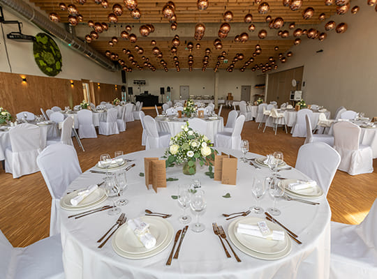 Großer schön eingerichteter Speisesaal mit runden Tischen in weißen Tischdecken und schönen Tischgestecken 