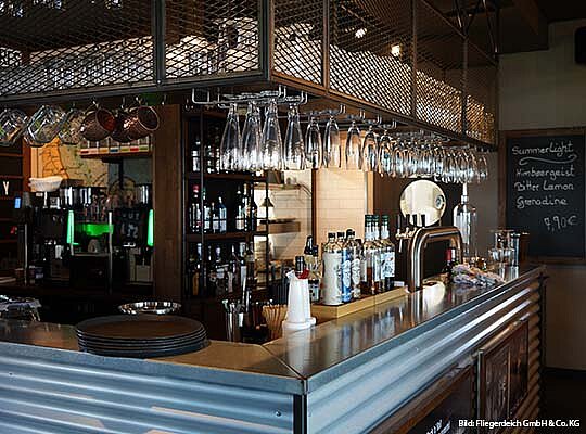 Krimidinner Fliegerdeich Hotel & Bar & Restaurant Blecherne Bar mit Gläsern über der Bar an einem Schrank hängend