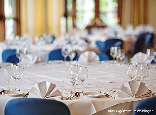 Gedeckter Tisch mit blauen Stühle, weißen Servietten und Gläsern beim