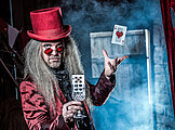 Der Zauberer wirft Karten in die Luft und hält ein Glas in der Hand - magisches Krimidinner