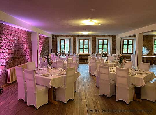 Saal mit Holzboden, in weiß gedeckte Tische, Steinwände beim Krimidinner Gründau