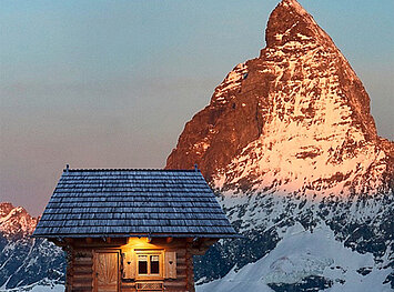 Sonnige Sicht auf einen Berggipfel mit einer Holzhütte davor