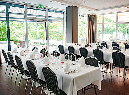 Großer Speisesaal mit riesigen Fensterfronten und langen Tischtafeln angerichtet für das Original Kriminal Dinner