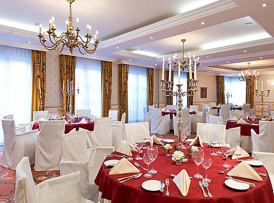 Großer Speisesaal mit rot dekorierten, runden Tischen. Angerichtet für das Kriminal Dinner Gotha.