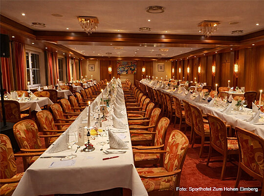 lange, gedeckte Tafeln im Speisesaal mit rotem Teppich