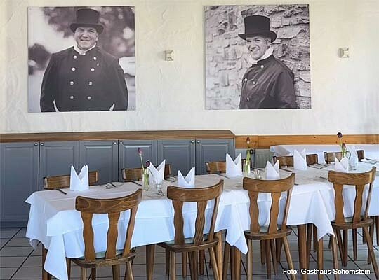 schön gedeckte Tische vor Wand mit Portraitbildern