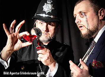 Zwei Männer untersuchen einen roten Diamant mit einer Lupe