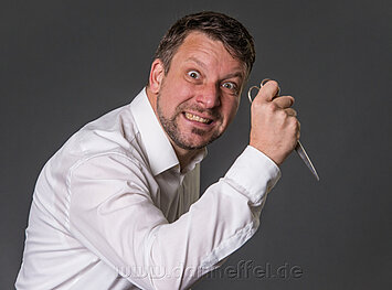 Mann mit irrem Blick hält Schere in der Hand - Krimidinner 