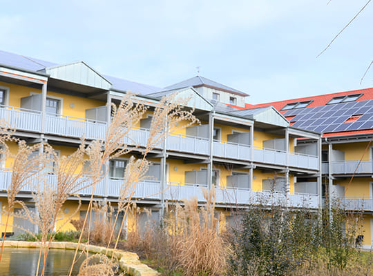 Blick vom Innenhof mit schönem Teich auf die Hotelzimmer mit Balkon.