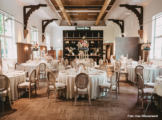 einladender Gastraum mit großen runden Tischen und Parkettboden