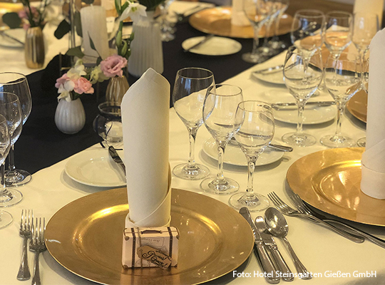 Ein Tisch ist mit goldenen Tellern und Besteck gedeckt 