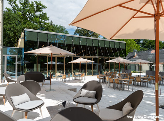 Außengastronomie vor modernem Gebäudeanbau aus Glas