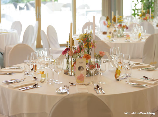 sehr elegant gedeckter großer runder Tisch mit Blumenarrangement