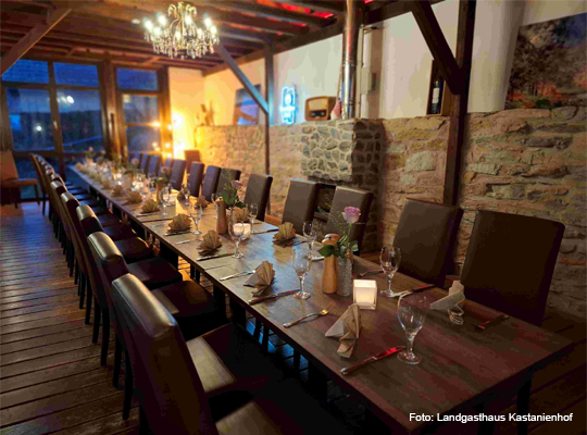 lange, gedeckte Tafel im Gastraum mit Steinwand