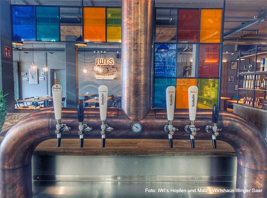Zapfanlage der Bar mit bunter Glaswand im Hintergrund