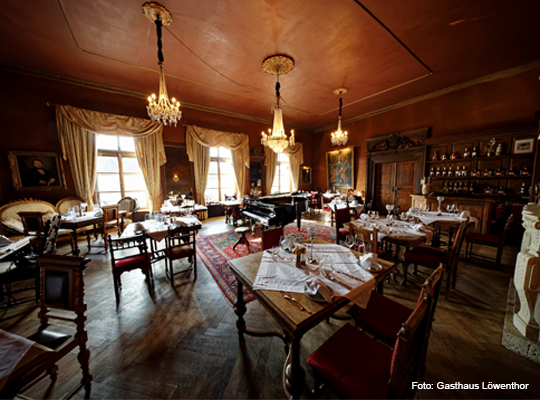 rustikaler Gastraum mit drei Kronleuchtern im Gasthaus Löwenthor