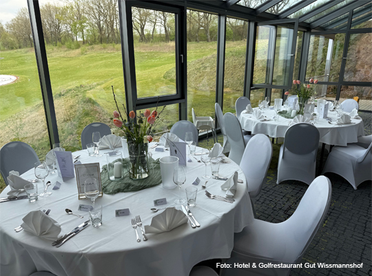 schön eingedeckte runde Tische vor Glasfront