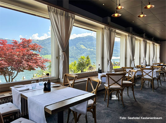Fensterfront mit Tischen im Gastraum mit Seeblick