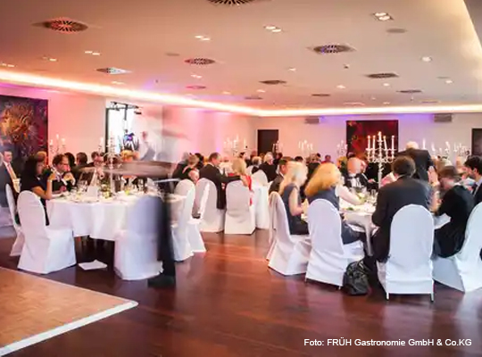 festlicher Veranstaltungssaal mit runden Tischen und Stühlen in Stuhlhussen