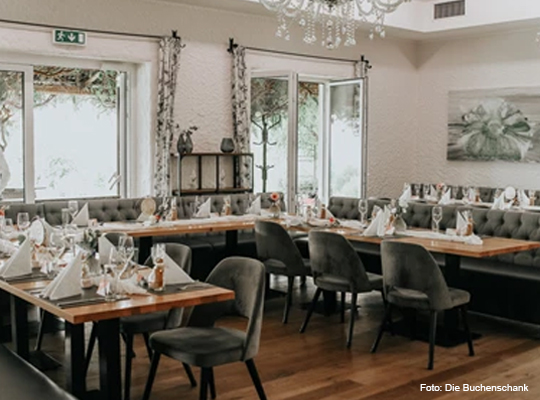 stilvoller Gastraum mit samtbezogenen Stühlen und Kronleuchter