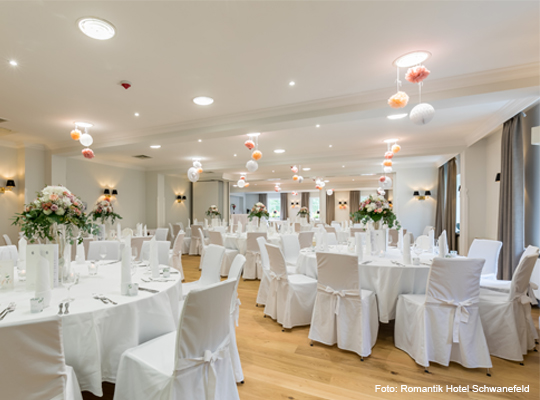 heller Festsaal mit großen runden Tischen