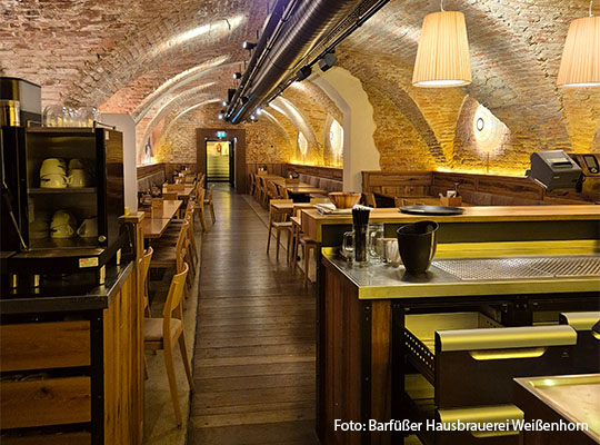 Langer Gang, mit Gewölbe Decke und Tischen, Ansicht ist von einer Bar aus.