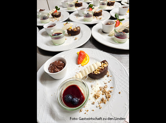 Ein vielfältiges Dessert ist auf weißen Tellern angerichtet 