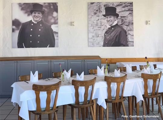 schön gedeckte Tische vor Wand mit Portraitbildern