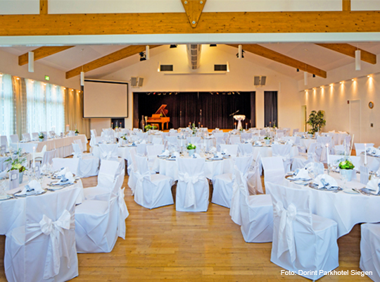 festlich gedeckte, große runde Tische im Veranstaltungssaal