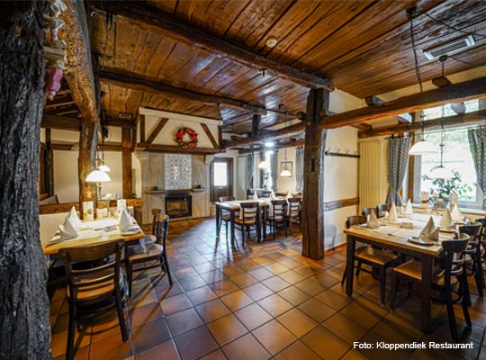 Blick in den rustikalen Gastraum mit Holzbalken und Holzdecke