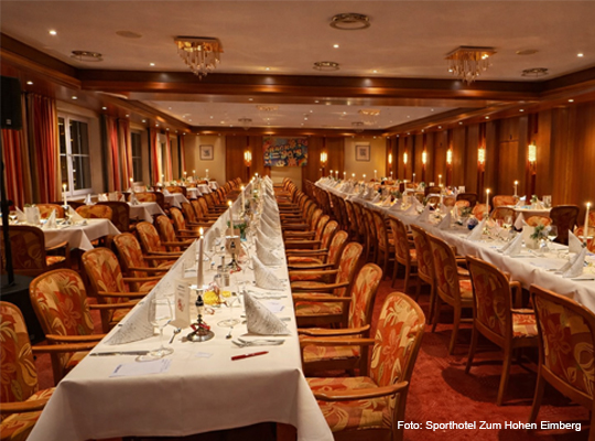 lange, gedeckte Tafeln im Speisesaal mit rotem Teppich