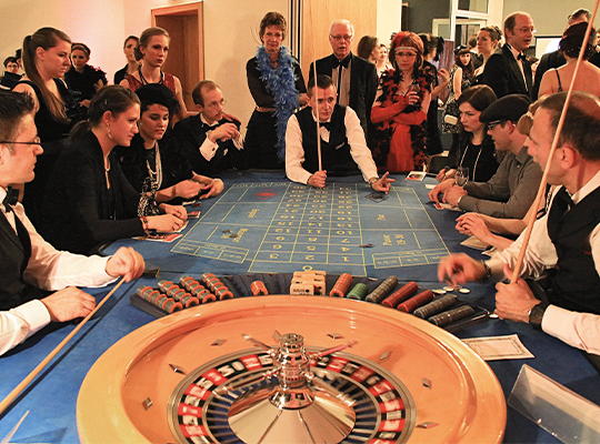 Casino-Party im zwanziger Jahre Style, Menschen versammeln sich um den Glücksspiel Roulette-Tisch.