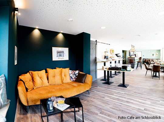 zu sehen ist ein gelbes Sofa, welches vor einer dunkel-Türkiesen Wand steht.