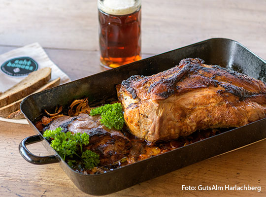 Leckerer Braten in einer Metallenen Auflaufform, vor dem Braten befindet sich ein Kühles Bier im Glas.