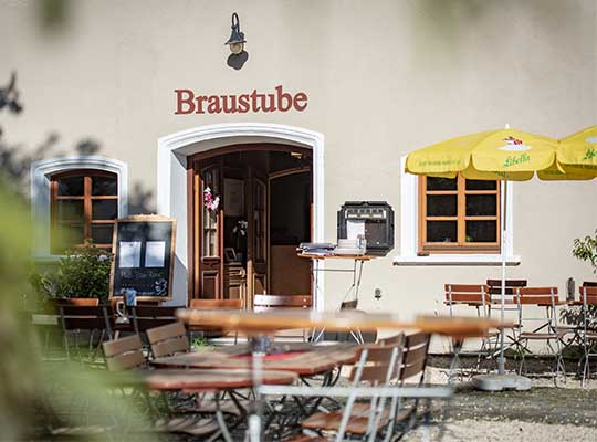 Eingang zum Brauereigasthof mit Blick auf den sommerlichen Biergarten beim Krimidinner