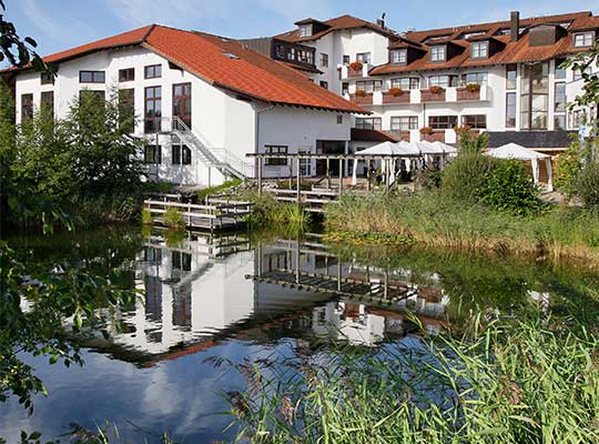 Außenansicht des Alpen Resort mit einem See vor der Haustüre beim Krimidinner