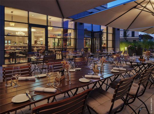 Außengastronomie mit Holztischen in gedämpftem Licht