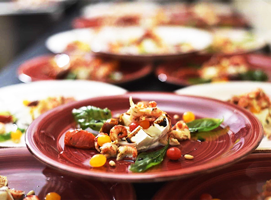 Lecker angerichtetes Essens-Menü serviert auf roten und weißen Tellern.