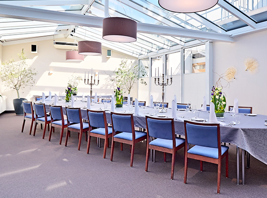 Weiße Tische und blaue Stühle dekoriert mit grünen Pflanzen und hochwertigem Besteck