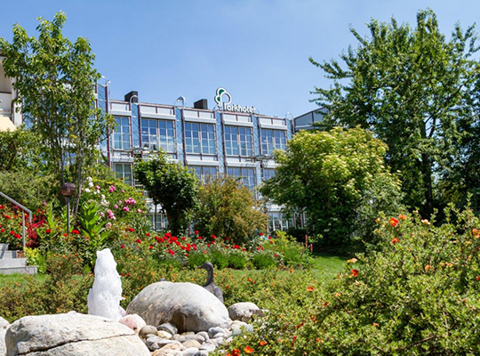 Gepflegte Grünflächen, helle Steine und Parkhotel im Hintergrund