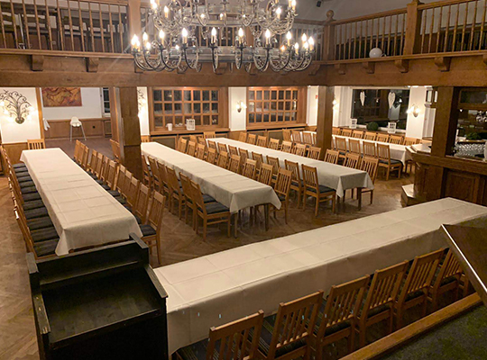 Großer Speisesaal mit langen Tafeln für alle Teilnehmer des Krimidinners