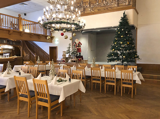 Weihnachtlich dekorierter Speisesaal mit dem Weihnachtsmann und einem riesige Weihnachtsbaum auf der Bühne