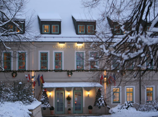 Verschneites Schlosshotel-Gebäude in der Abenddämmerung und schöner Beleuchtung