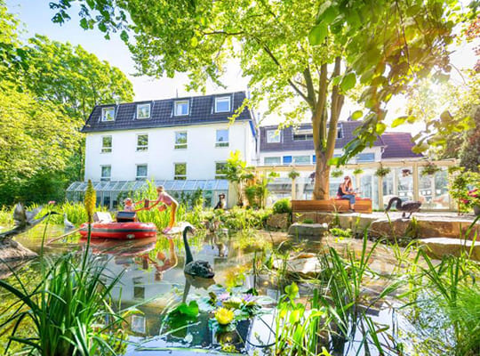 Außenansicht des idyllisch gelegenen Gartenhotels mit schönem Teich im Vordergrund