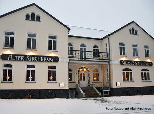 Außenansicht des Restaurants Alter Kirchkrug mit beleuchteten Schildern beim Krimidinner Flensburg