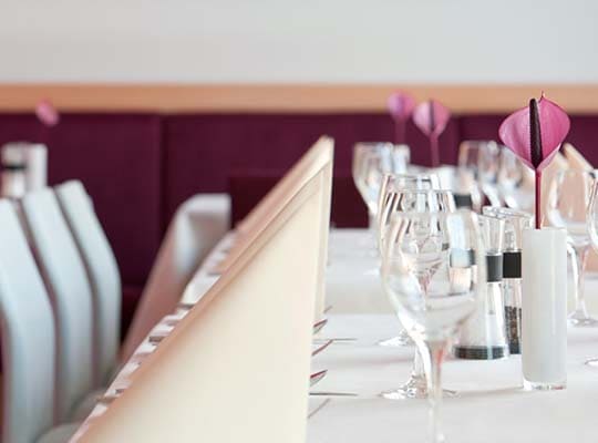 Schön dekorierter Esstisch im Restaurant mit beigen Servietten und Weingläsern