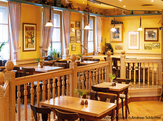 Ein Raum in einem Restaurant, dass mit Holztischen und Stühlen ausgestattet ist. 